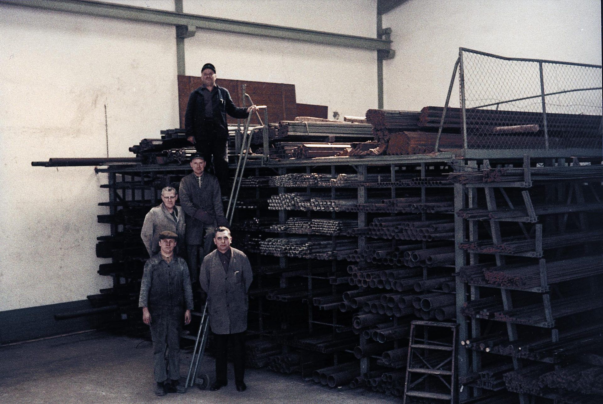 Mitarbeiter vor gestapeltem Stahl im Lager, 1962