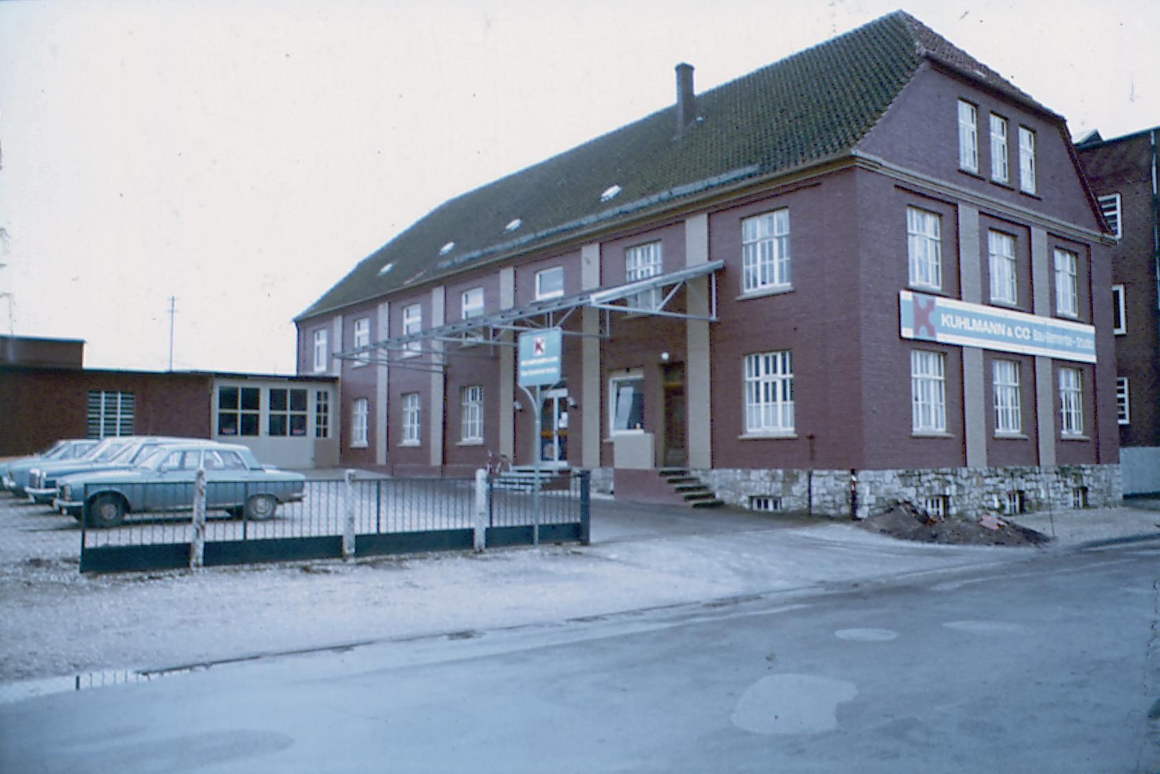 Firmengebäude aus Backstein mit Fahrzeugen davor, 1970