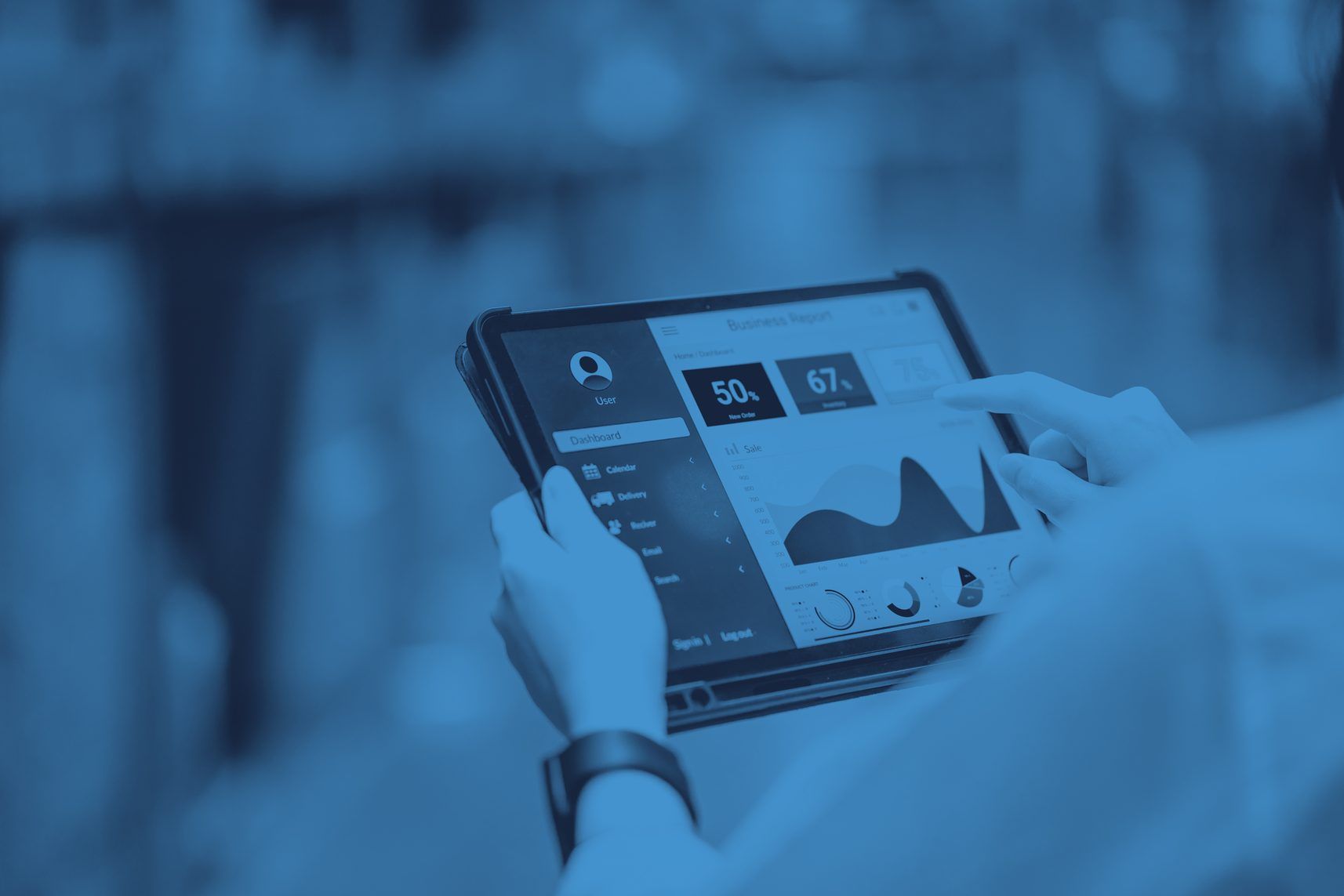 Hand hält ein Tablet mit Auswertungs-Dashboard, im Hintergrund unscharf eine Lagerhalle