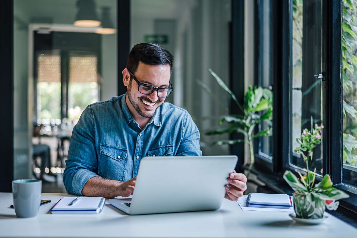 Mitarbeiter arbeitet am Laptop an einem hellen Schreibtisch