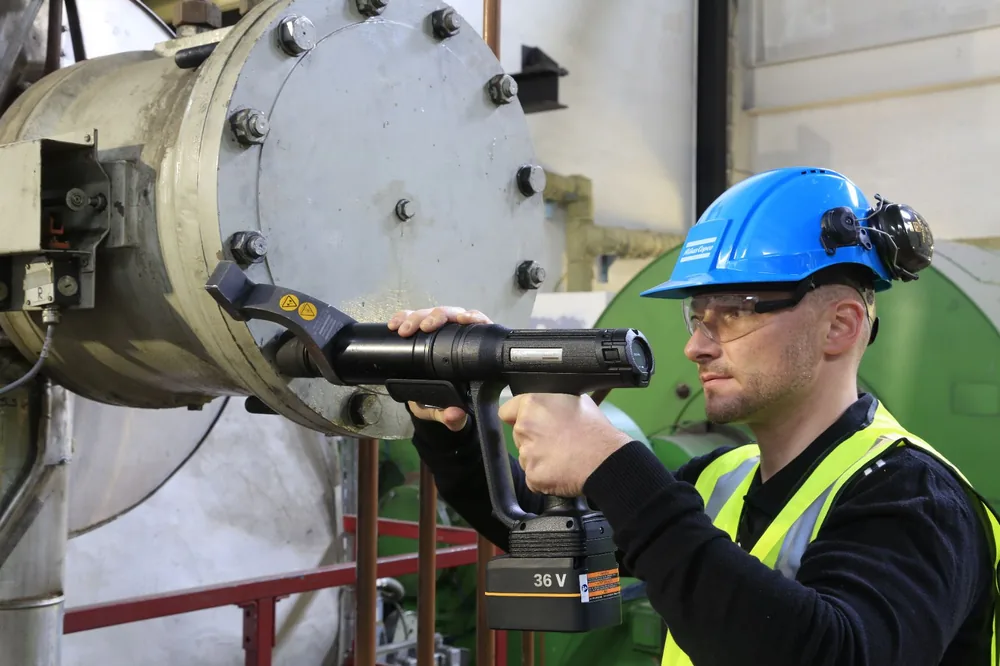 Atlas-Copco-Akkuschrauber mit Reaktionsarm an einer Flanschverschraubung